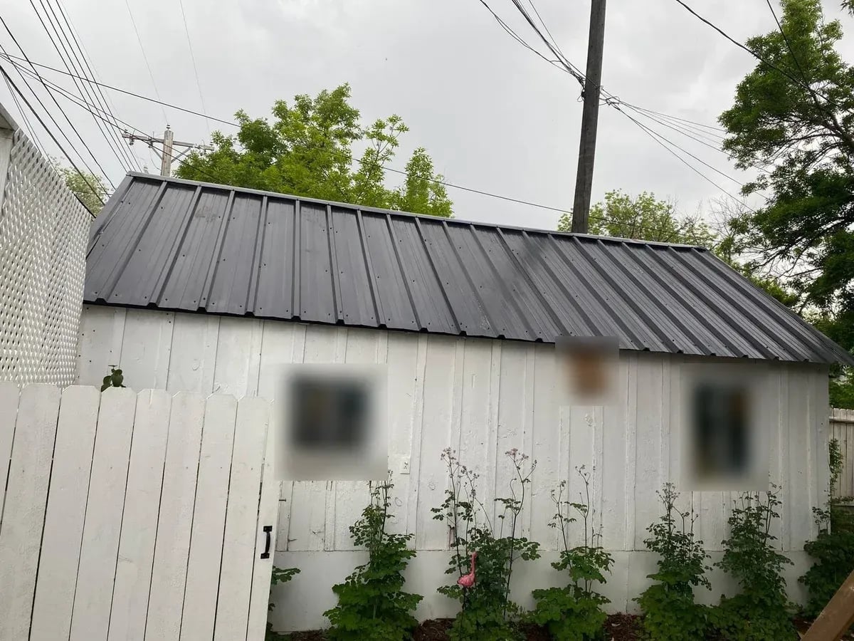 Black standing seam metal roof on a small white cottage