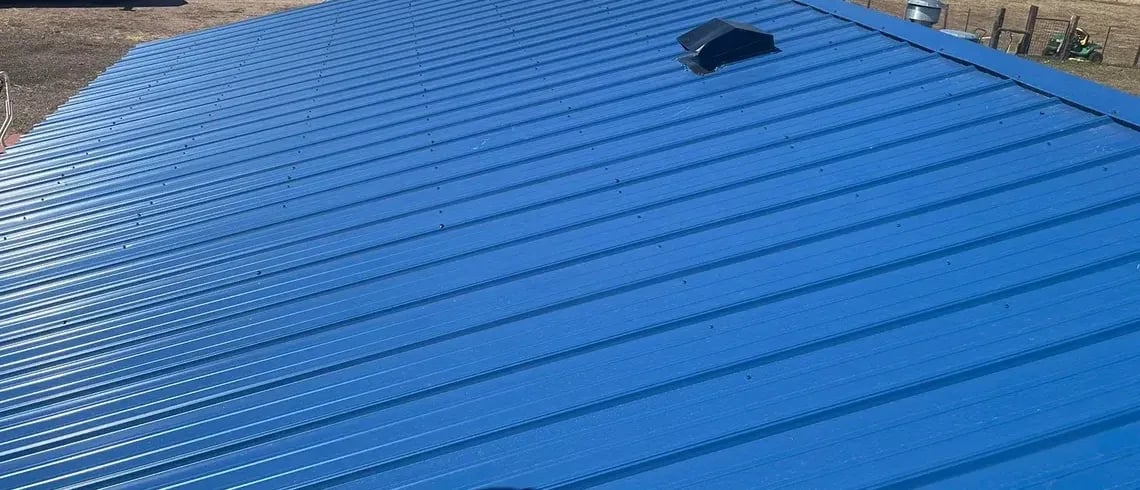 Blue ribbed metal roof panels with a roof vent