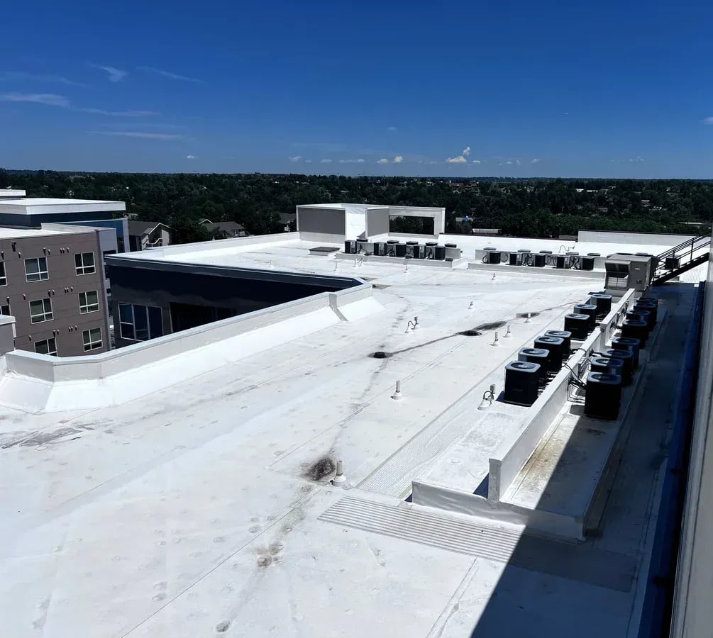 White TPO roof sections stepping between building wings lined with rooftop units
