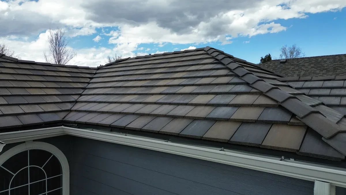 Dark brown flat concrete tile roof above an arched window
