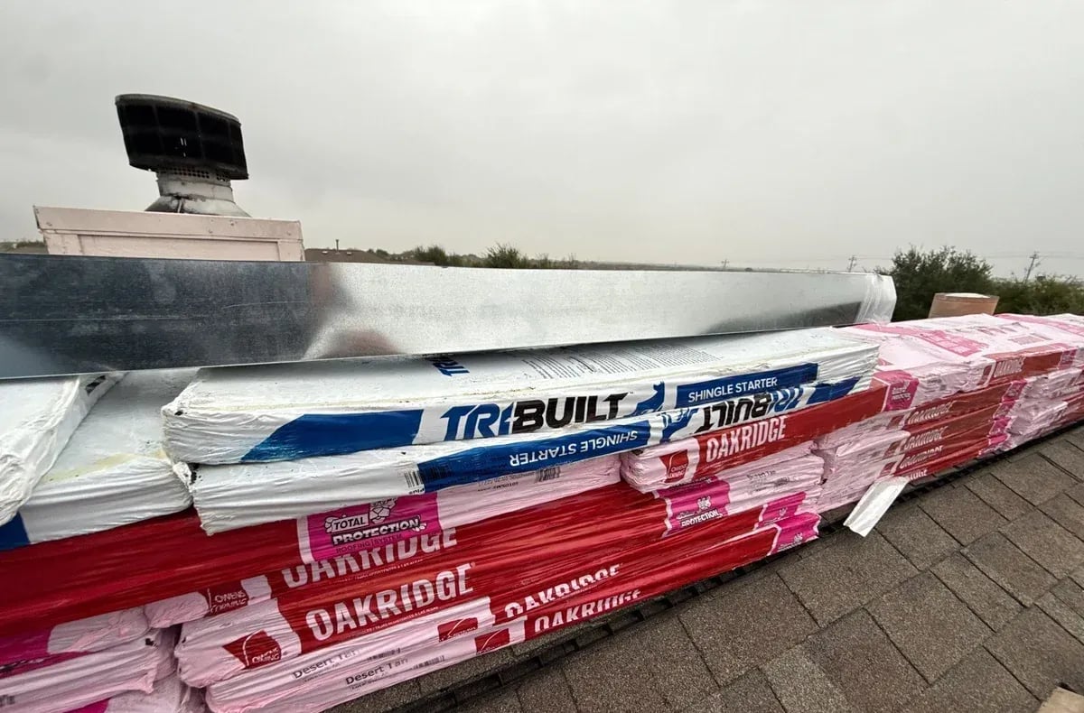 Owens Corning Oakridge shingle bundles and ridge cap boxes stacked on a roof ready to install