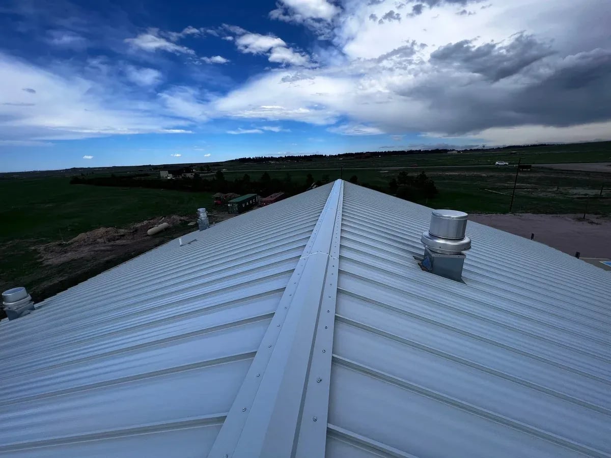 Standing seam ridge cap with a roof vent and open prairie beyond