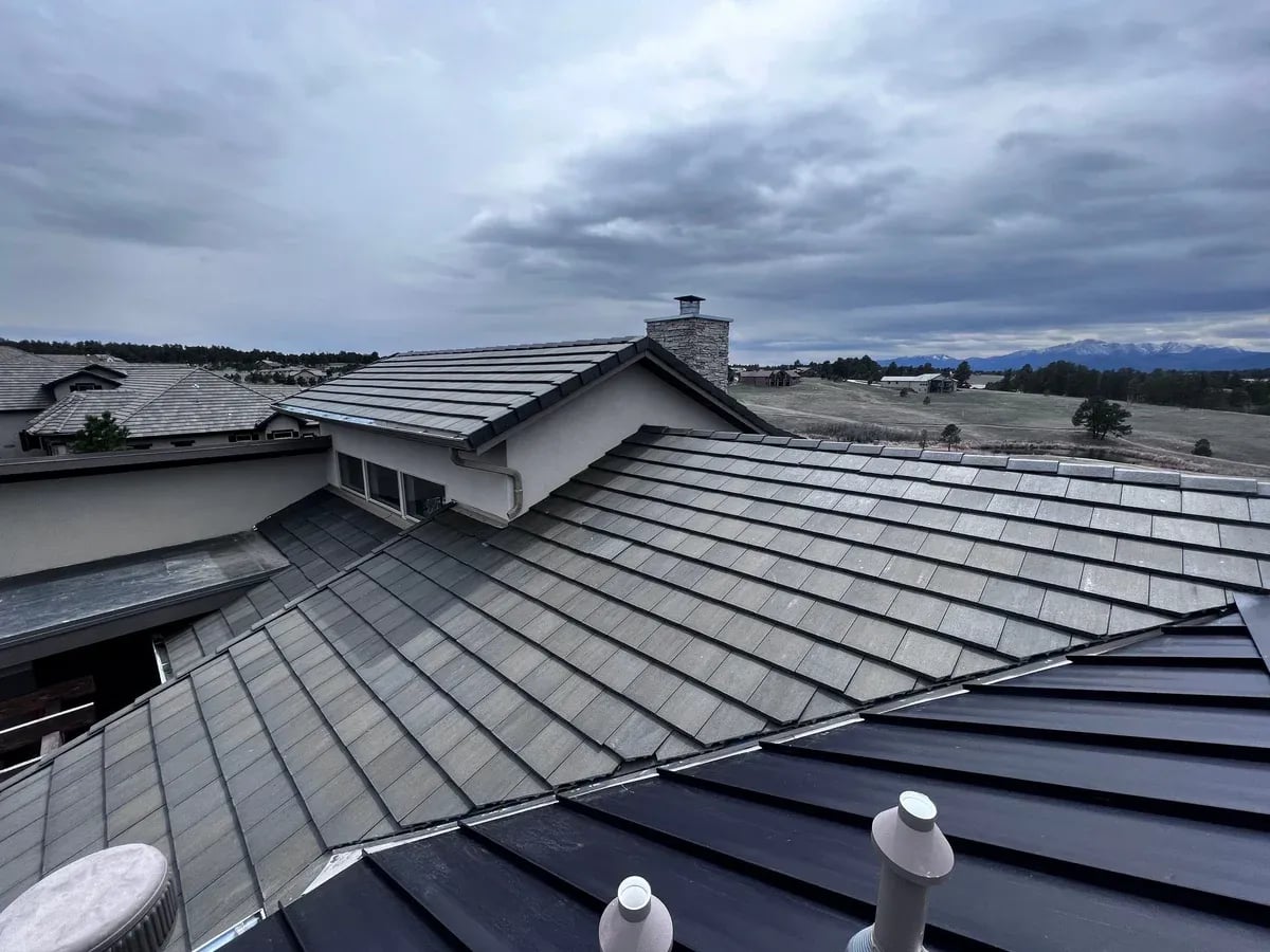 Gray stone-coated steel roof sections above a dark standing seam metal roof