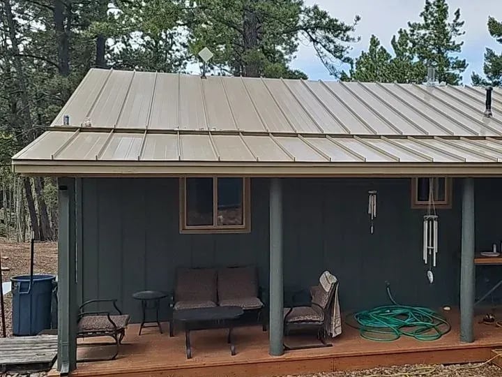 Tan standing seam metal roof over a covered porch