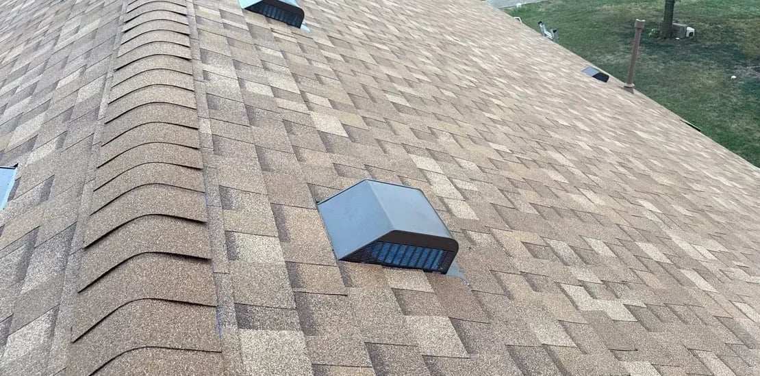 Finished brown-tan architectural shingle roof with a box vent near the ridge