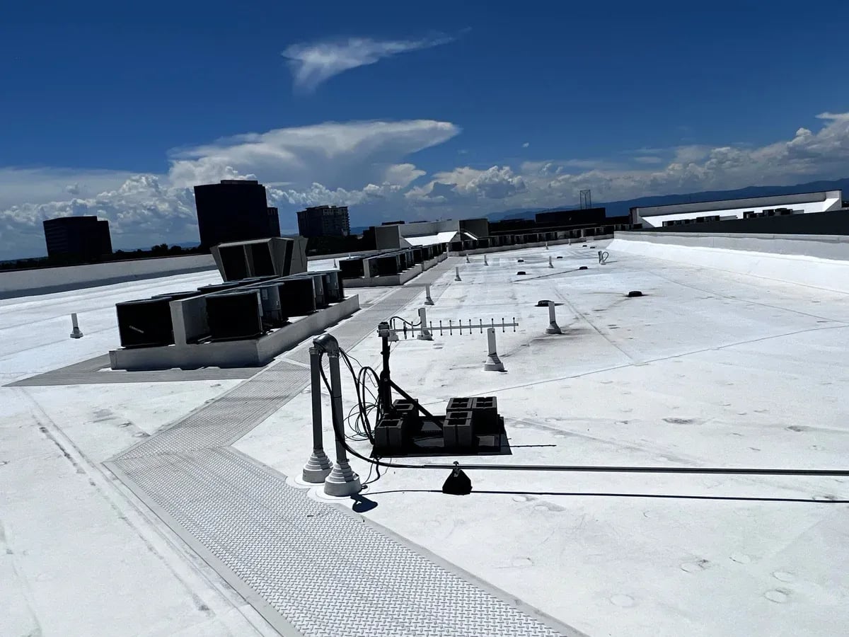 Large white TPO commercial roof with rooftop HVAC units and the Front Range on the horizon