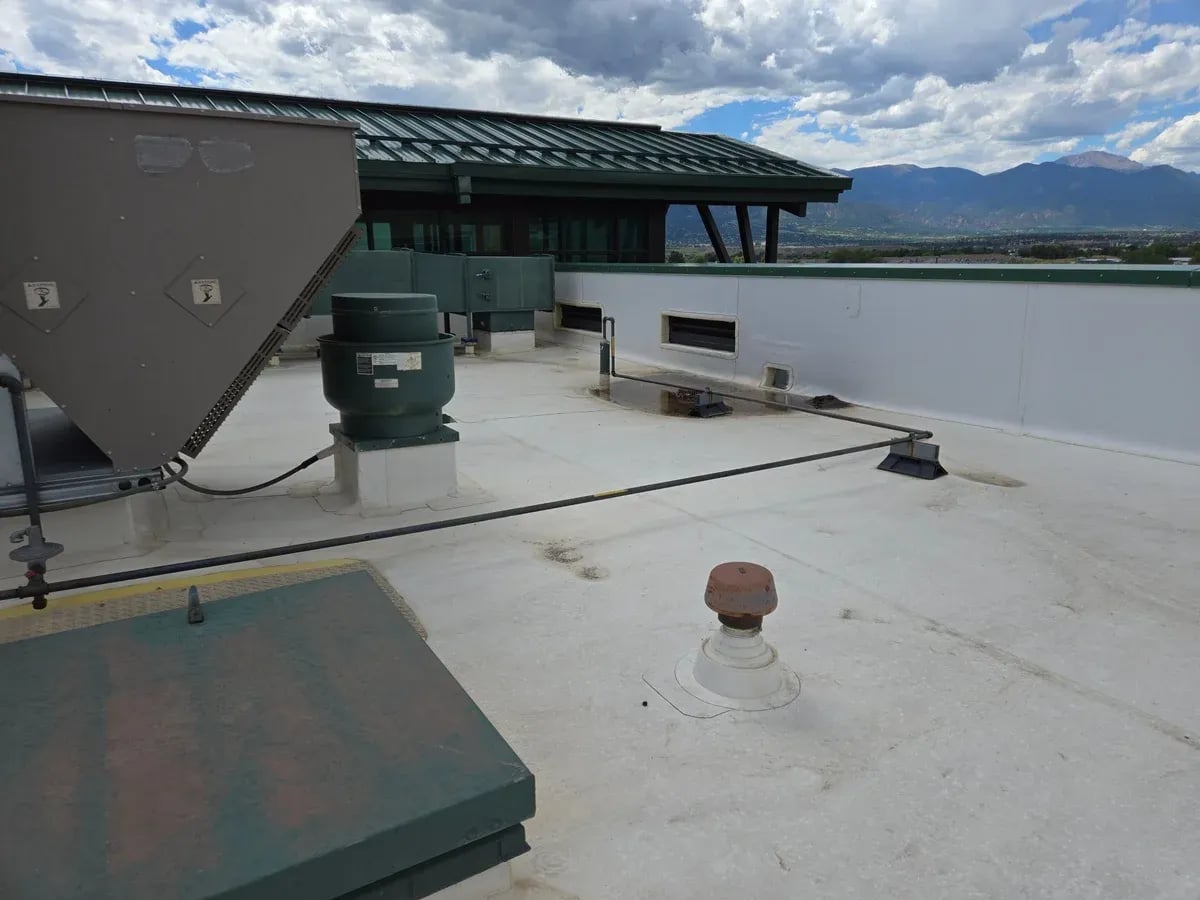 White TPO flat roof with rooftop equipment and mountains in the distance